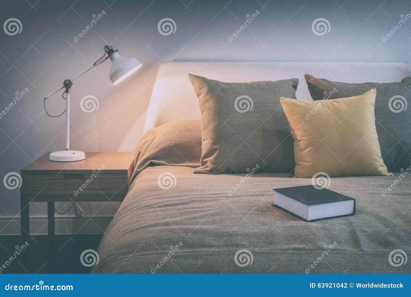 cozy bedroom interior with book and reading lamp on bedside table