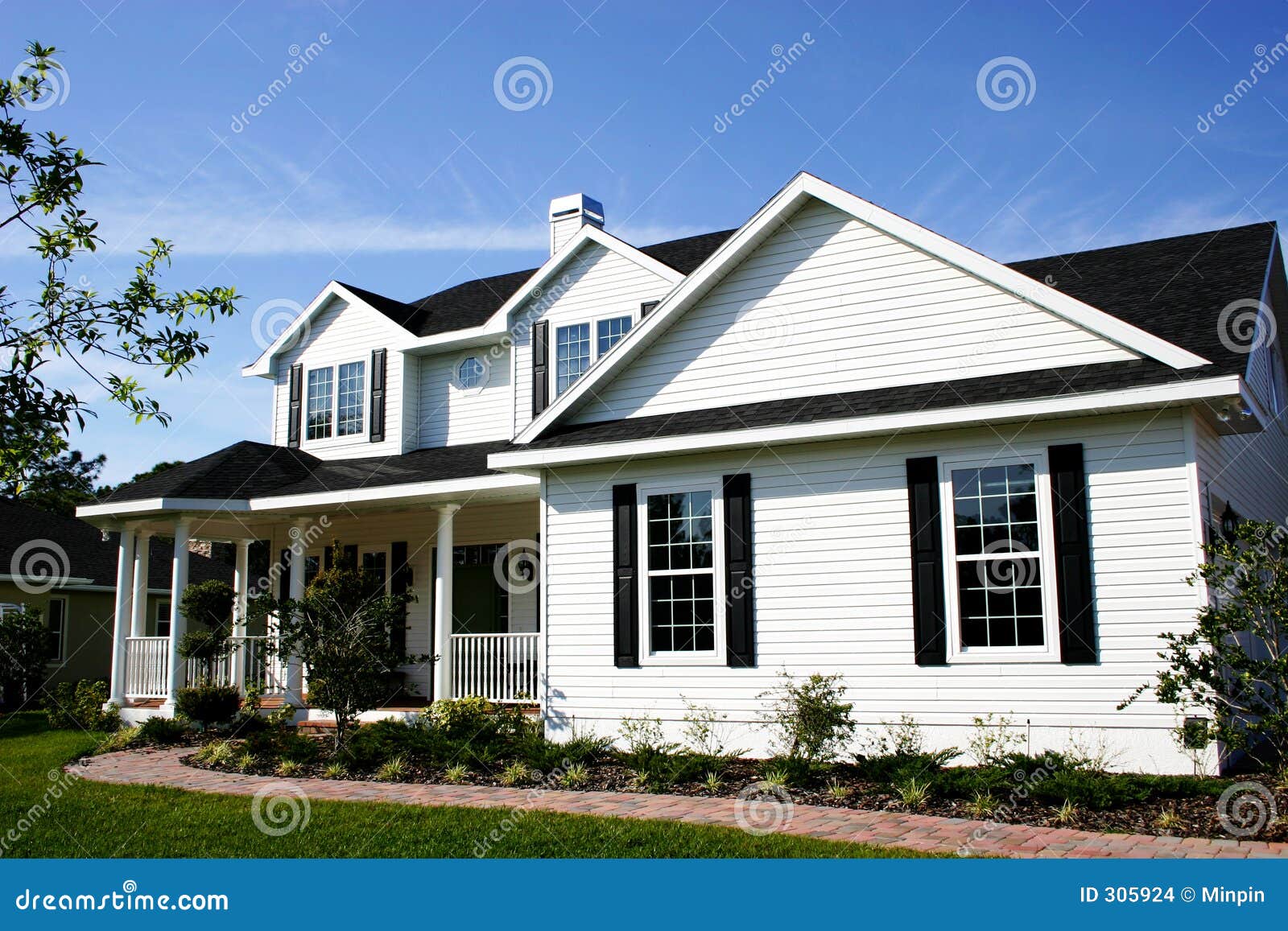 White cozy country home with green shutters,gables, and columns on