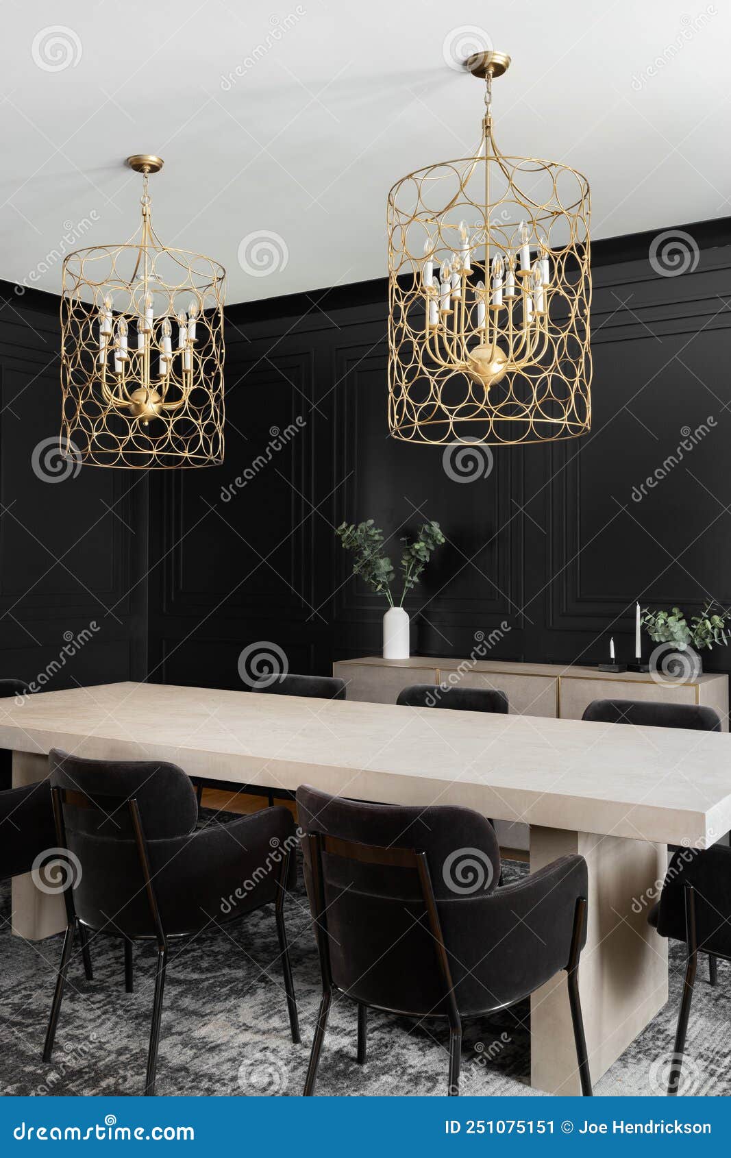 a black dining room with wainscoting walls and gold chandelier.