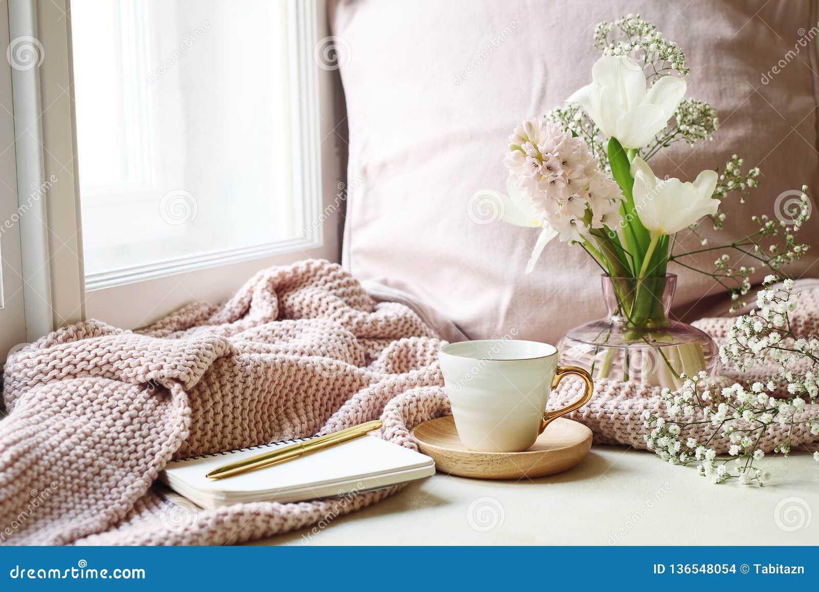 cozy easter, spring still life scene. cup of coffee, opened notebook, pink knitted plaid on windowsill. vintage feminine