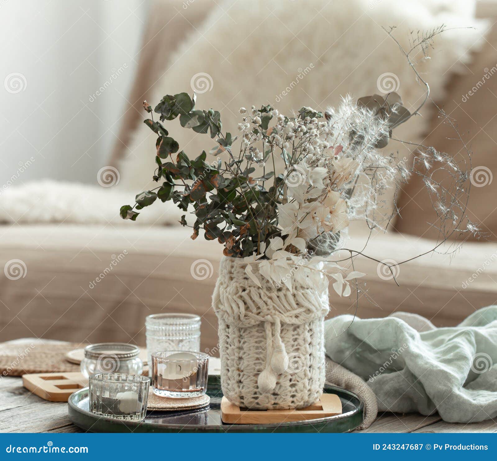 A cozy composition with candles, dried flowers in a vase and a knitted  element. Stock Photo by puhimec