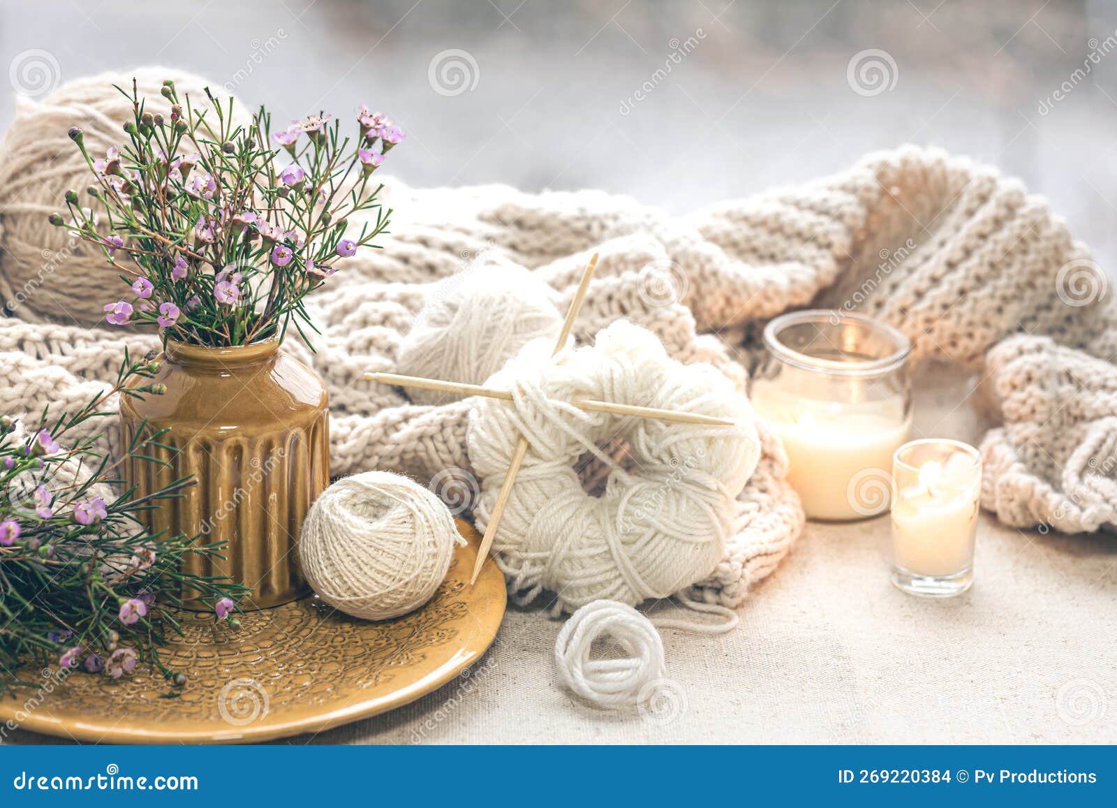 A cozy composition with candles, dried flowers in a vase and a knitted  element. Stock Photo by puhimec