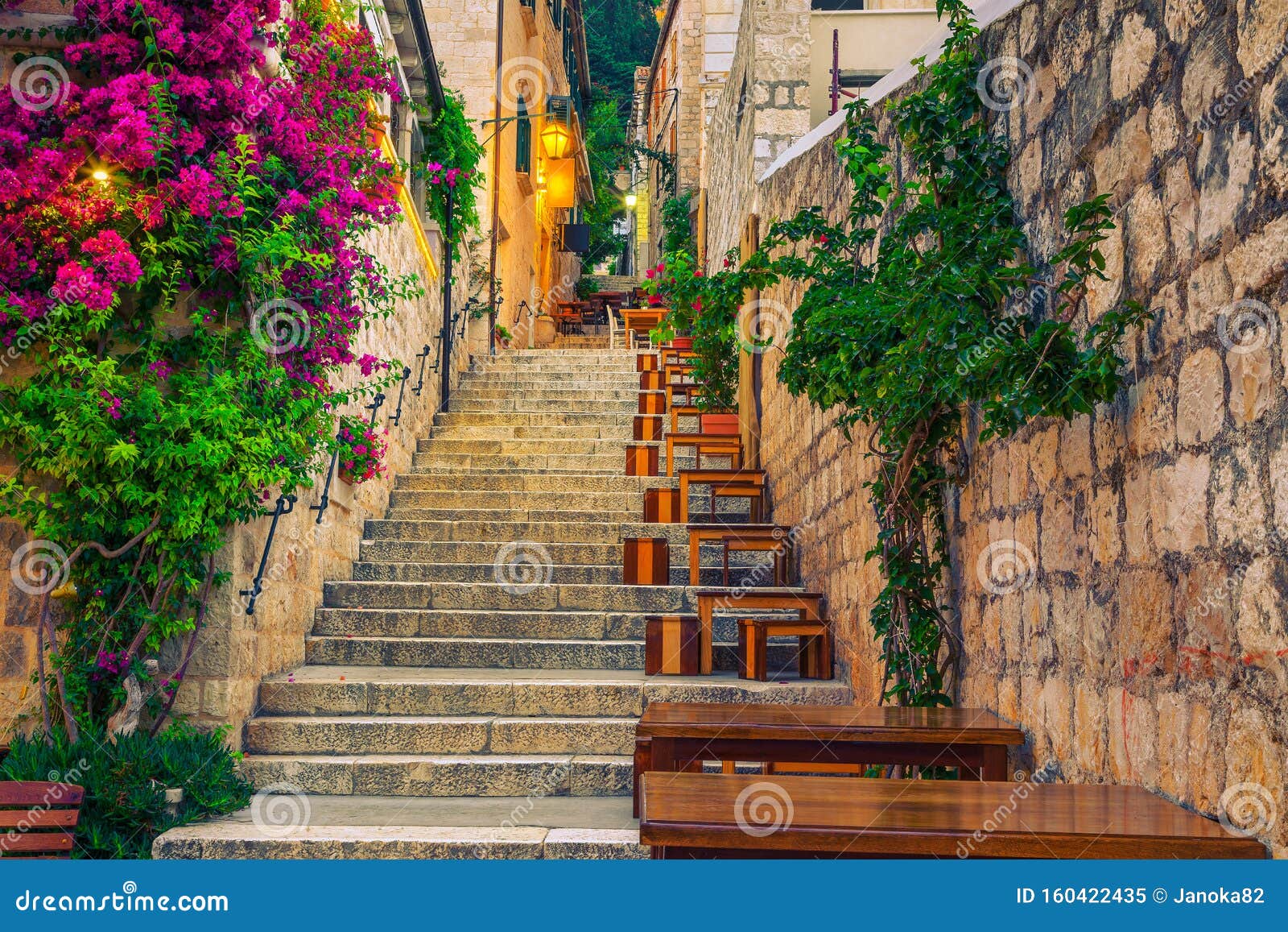 narrow street and street cafe decorated with flowers, hvar, croatia