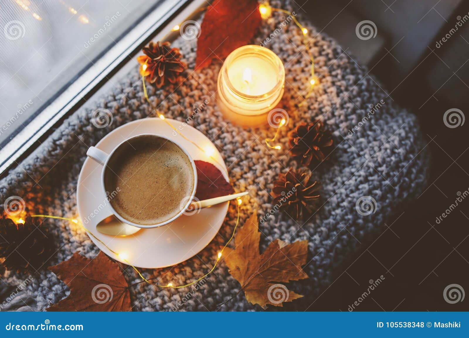 cozy winter or autumn morning at home. hot coffee with gold metallic spoon, warm blanket, garland and candle lights