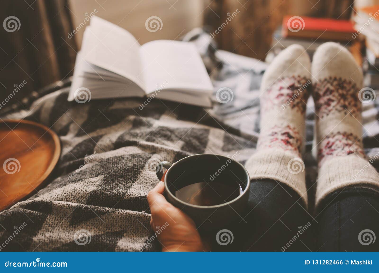 cozy winter day at home with cup of hot tea, book and warm socks