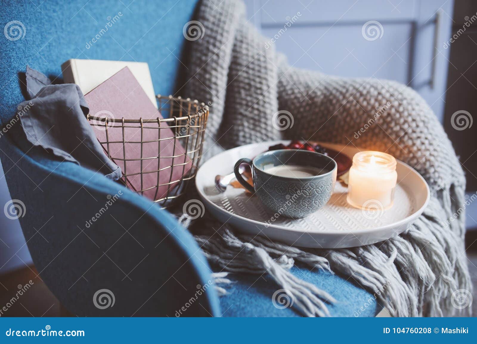 cozy winter weekend at home. morning with coffee or cocoa, books, warm knitted blanket and nordic style chair. hygge concept.