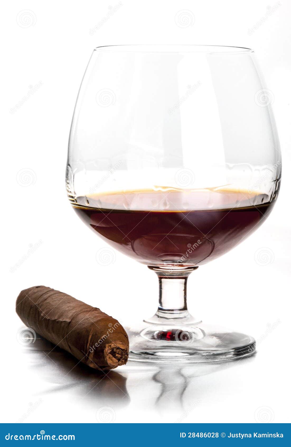 Coñac y cigarro. Vidrio del coñac y del cigarro en el fondo blanco