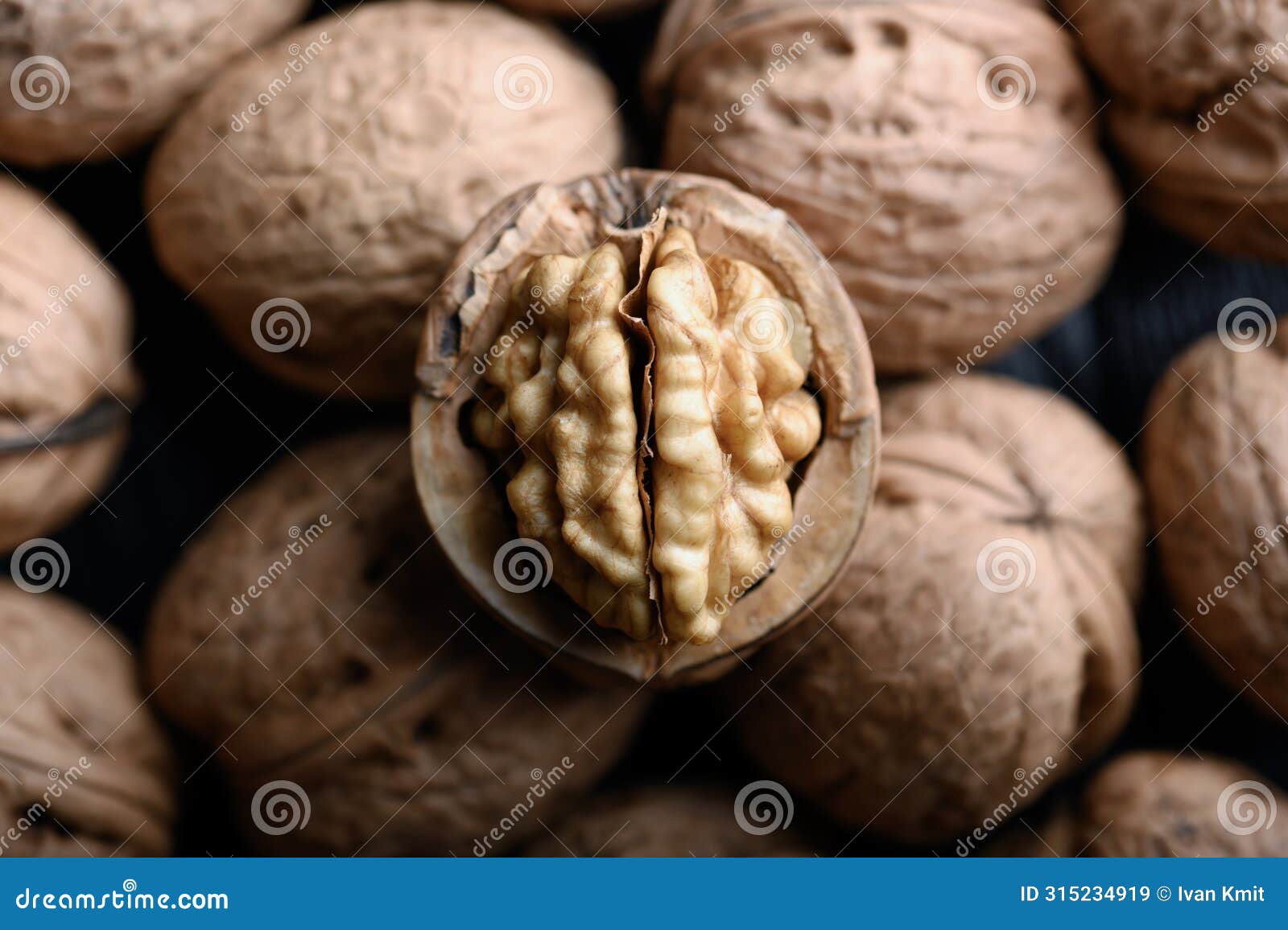 cracked walnut with kernels on heap of whole walnuts