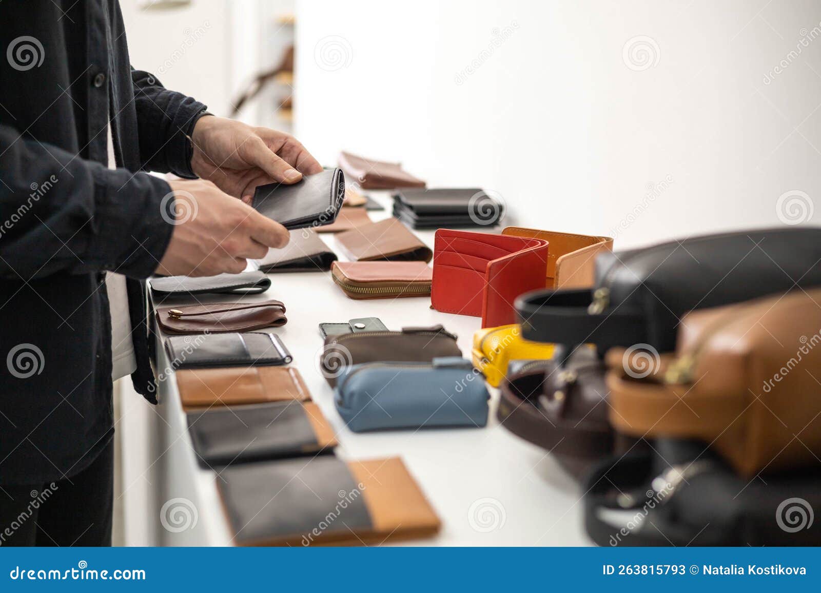 craftsman hands laying out leatherwork on wooden showcase at leather workshop. handwork accessories