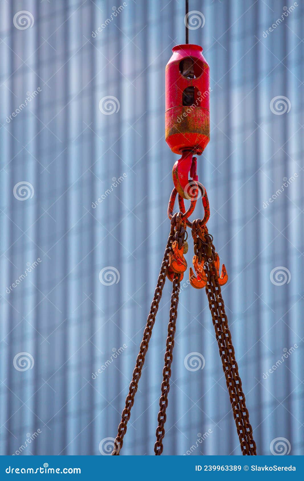 crane hoisting block with hook on steel chain on steel rope. glass facade of a modern skyscraper in the background. loading\