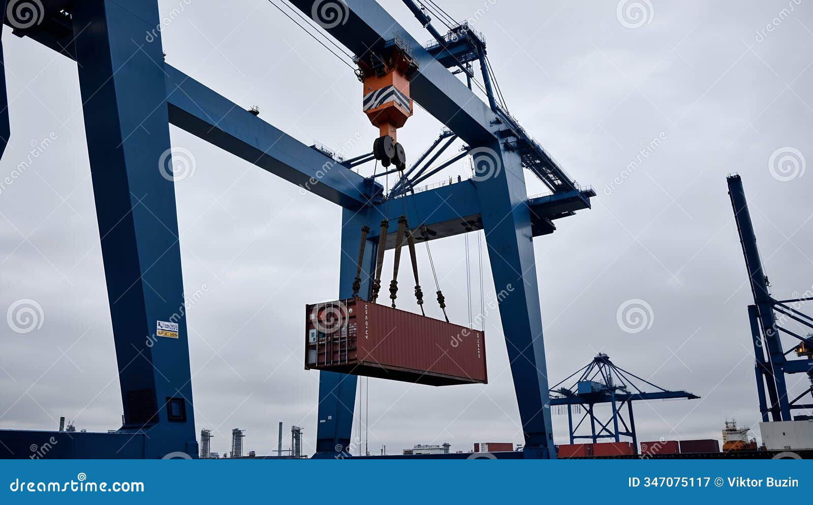 crane lifting a shipping container at a busy port during overcast weather in the late afternoon