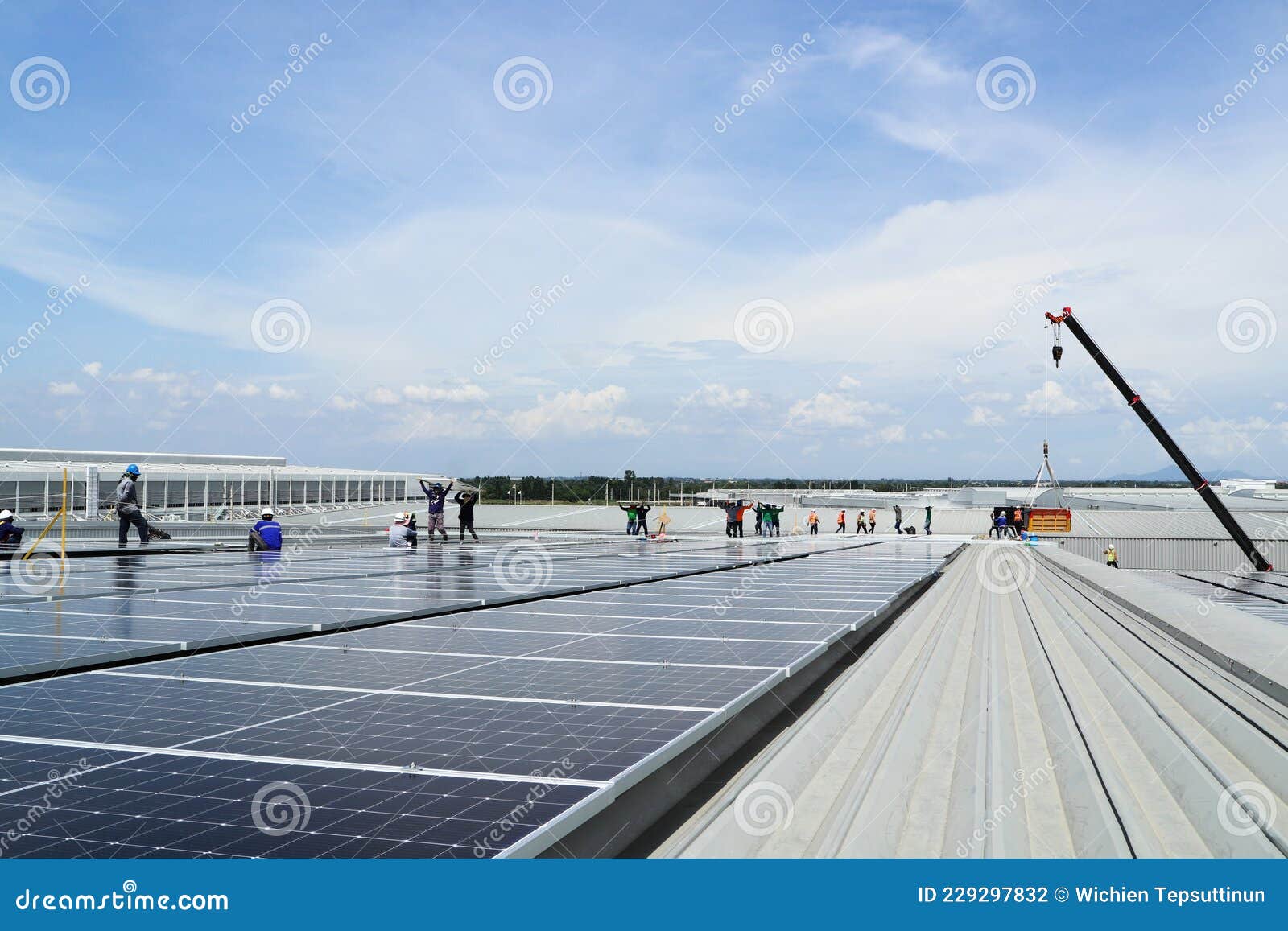 crane uploading solar panels on roof with installation workers