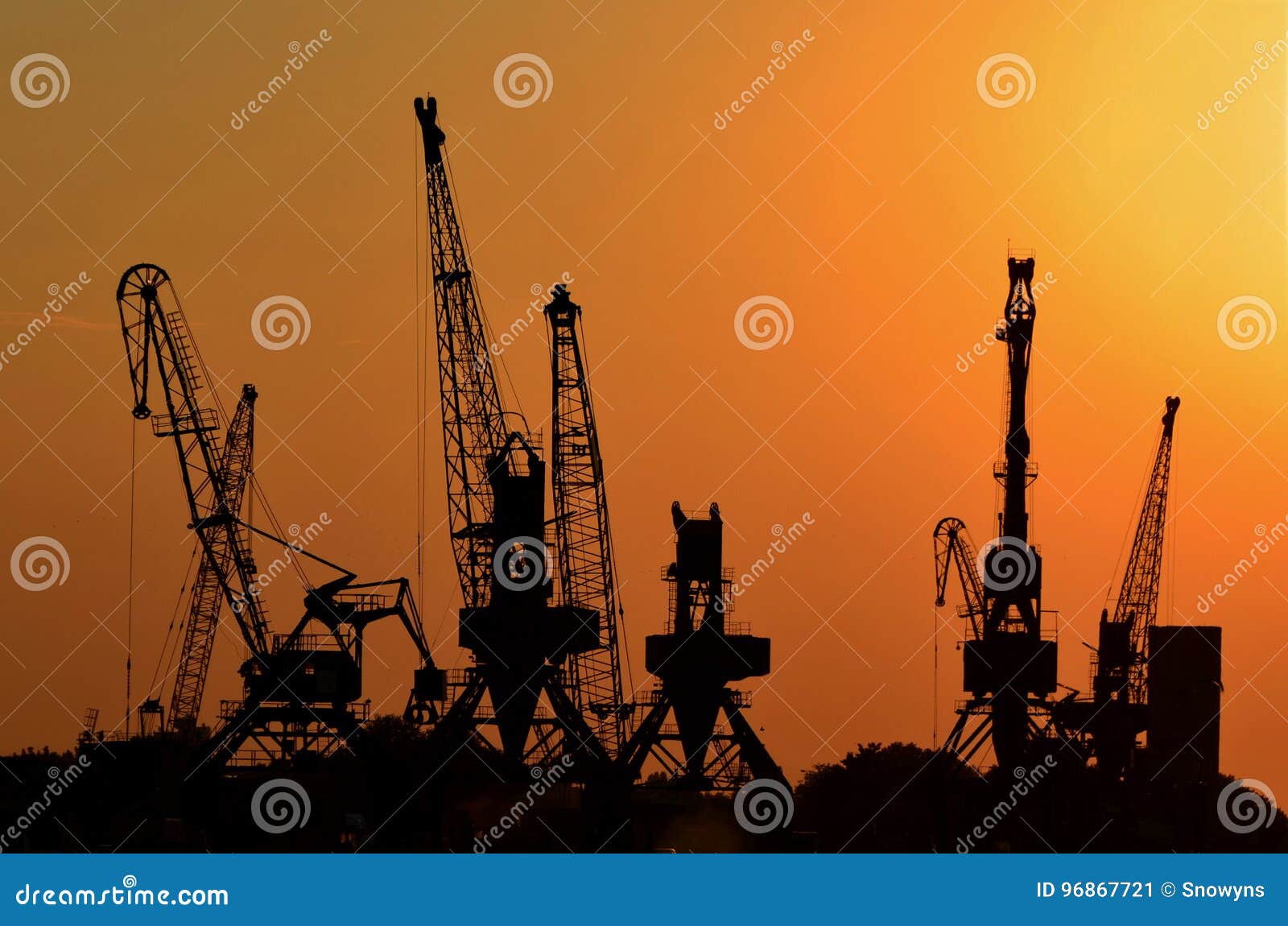 cranes for loading containers onto freighters or cargo ships in the port at sunset