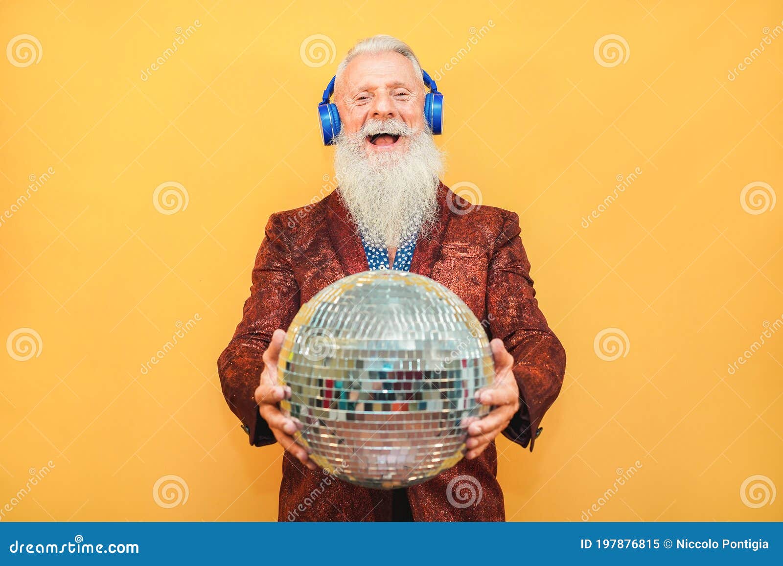 crazy hipster man listening music with headphones while holding disco ball - party concept
