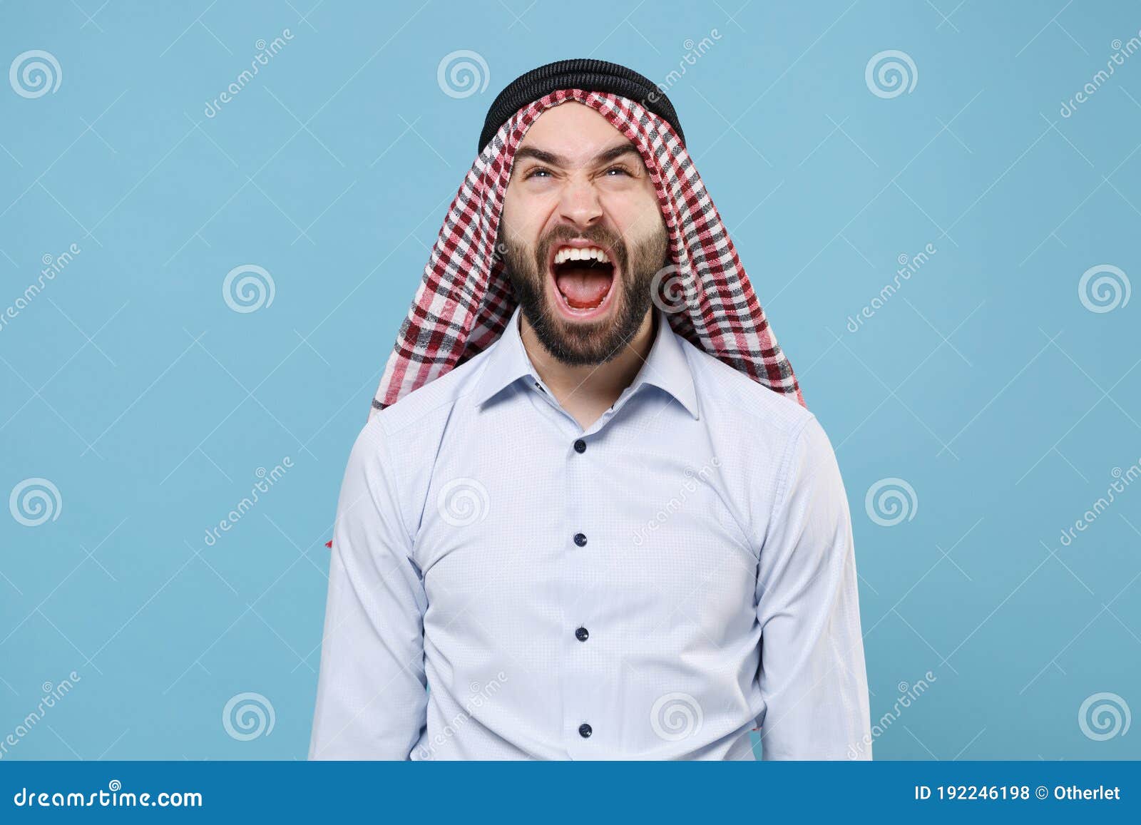 crazy young bearded arabian muslim man in keffiyeh kafiya ring igal agal casual clothes  on pastel blue