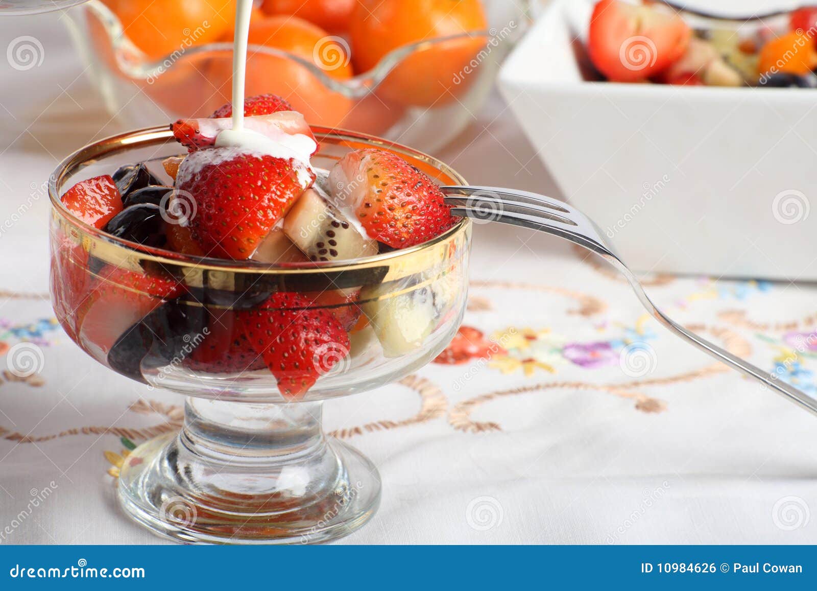 Cream Pouring on Fresh Fruit Salad in a Glass Bowl Stock Photo Image