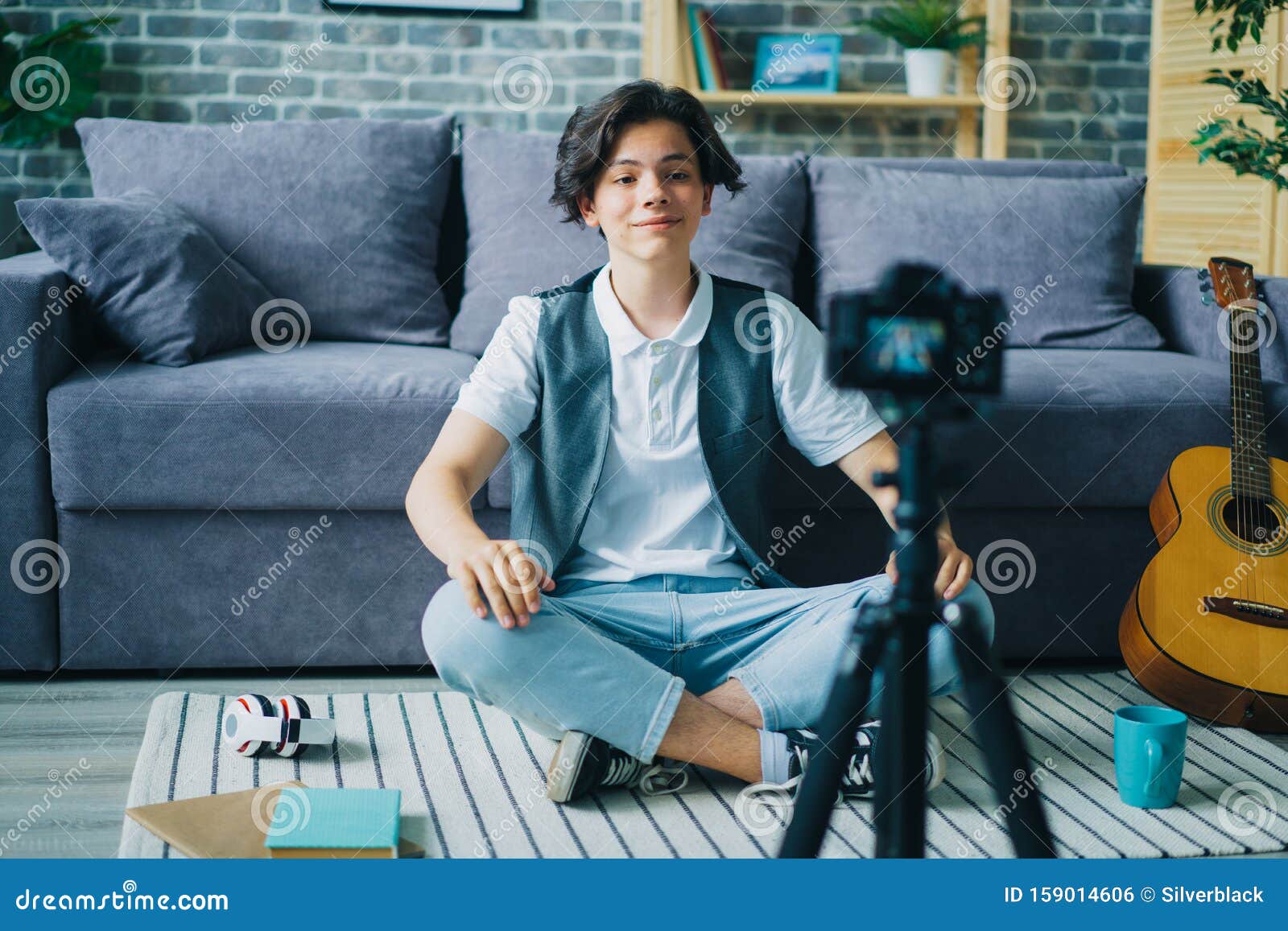 creative boy vlogger recording video for online vlog speaking on floor at home