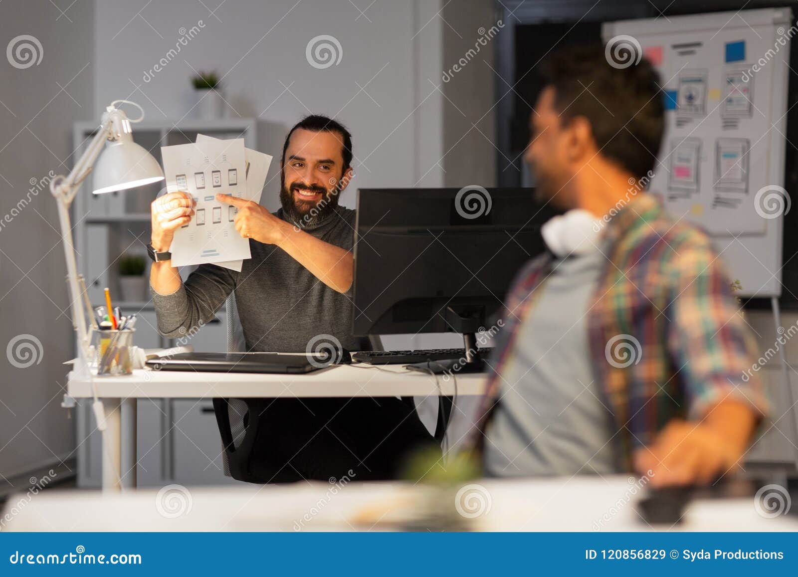 Creative Man Showing Papers To Colleague At Office Stock Image