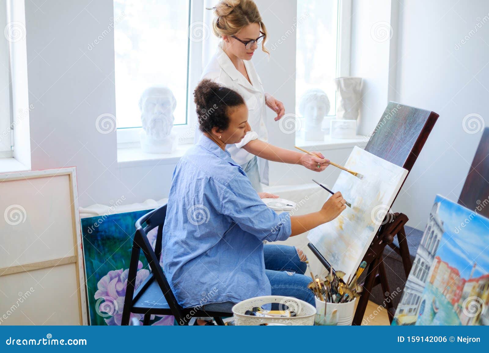 creative painter and her protege working in a studio