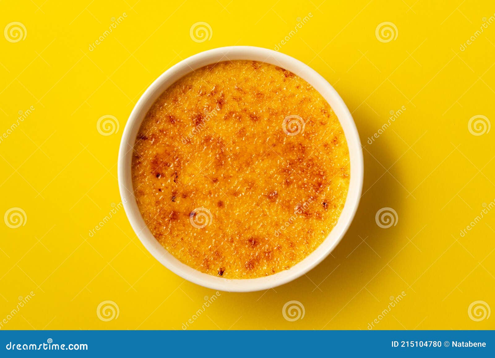 creme brulee in ramekin  on bright yellow color background. close up