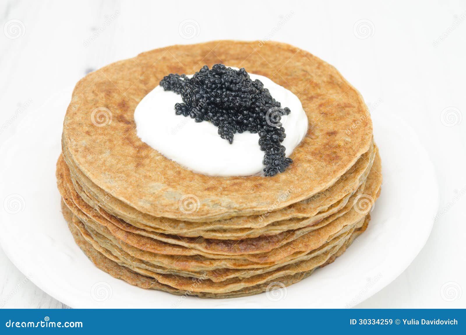 Crepes de patata con crema agria y el caviar en el fondo blanco. Crepes de patata con crema agria y el caviar en el primer blanco del fondo