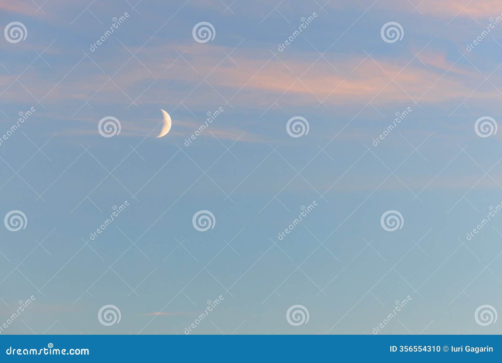 crescent moon in tranquil evening sky with soft pink clouds
