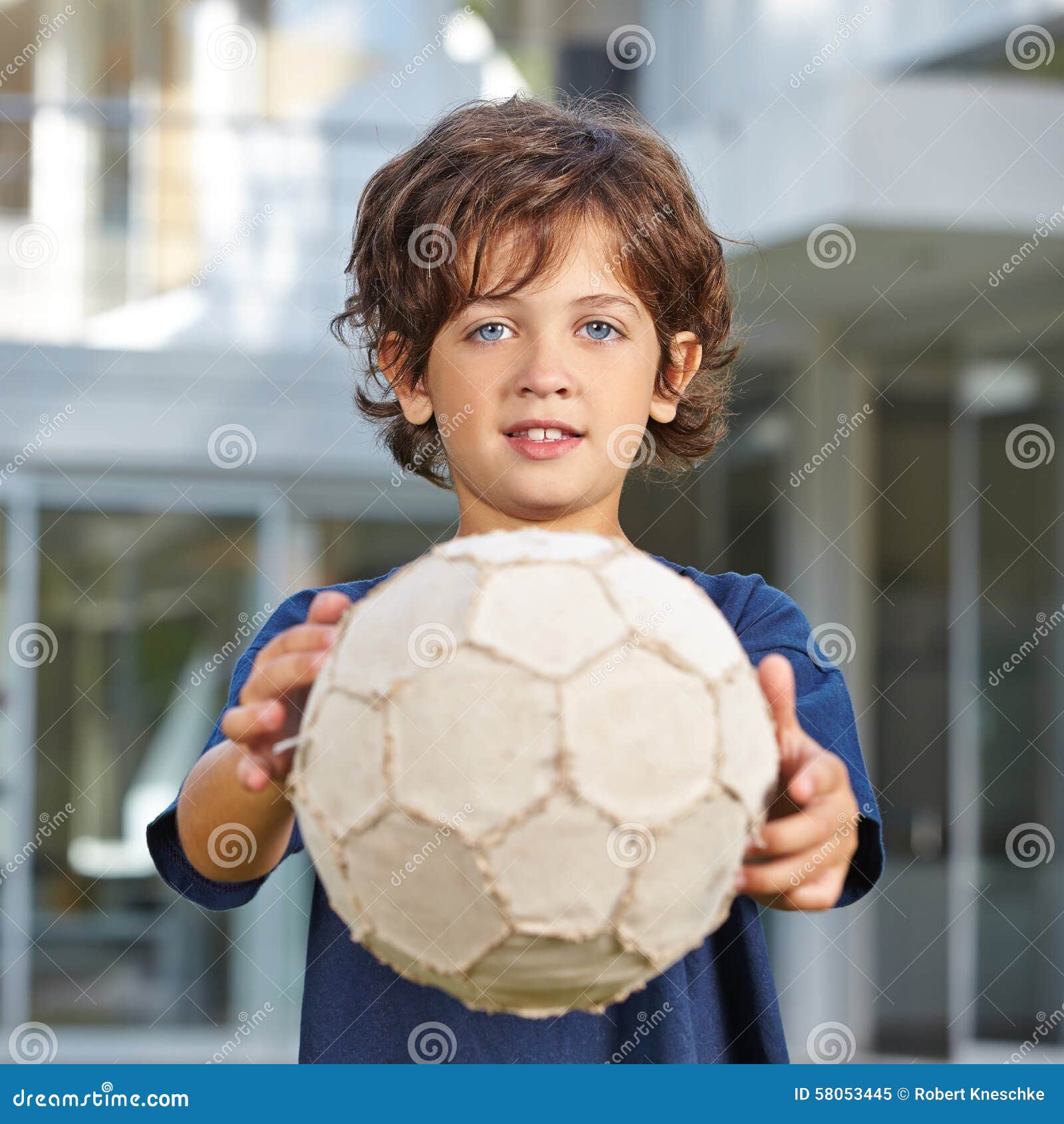 Um garoto segurando a velha bola de futebol antes de começar um jogo de  futebol