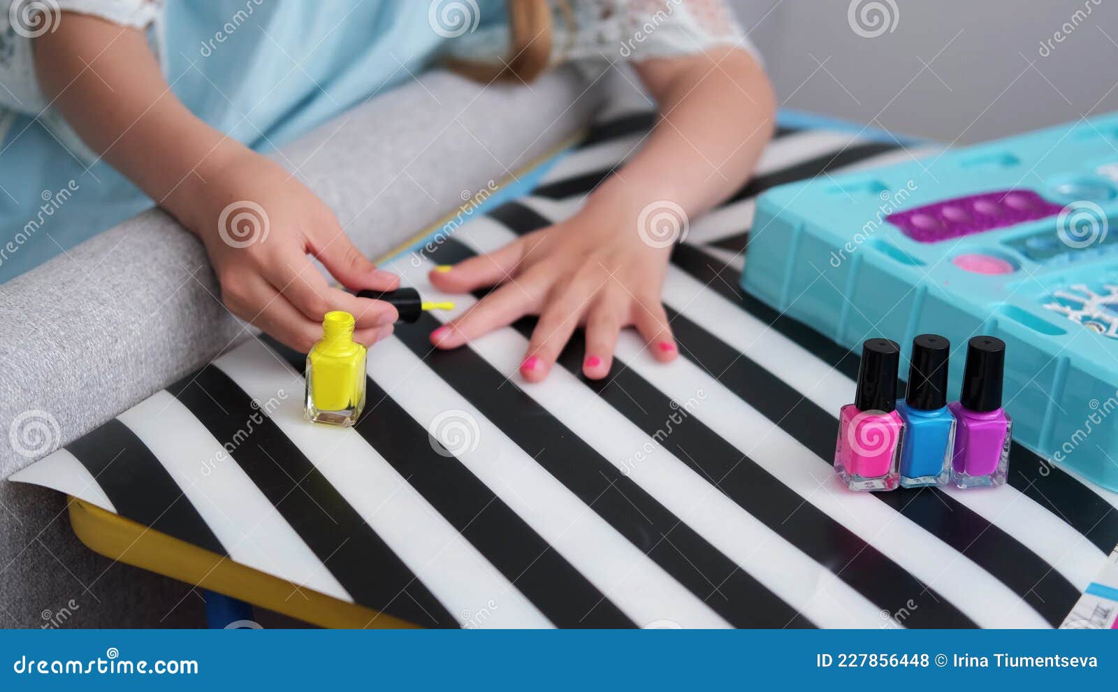 A Criança Senta-se À Mesa E Pinta As Unhas Com Esmalte Amarelo