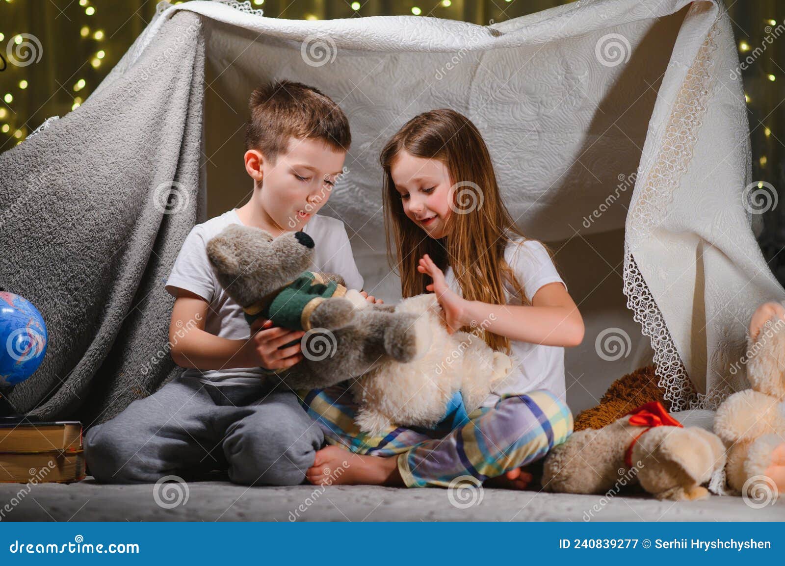 Quarto de criança com tenda e jogo de brincar com ursinho no chão.