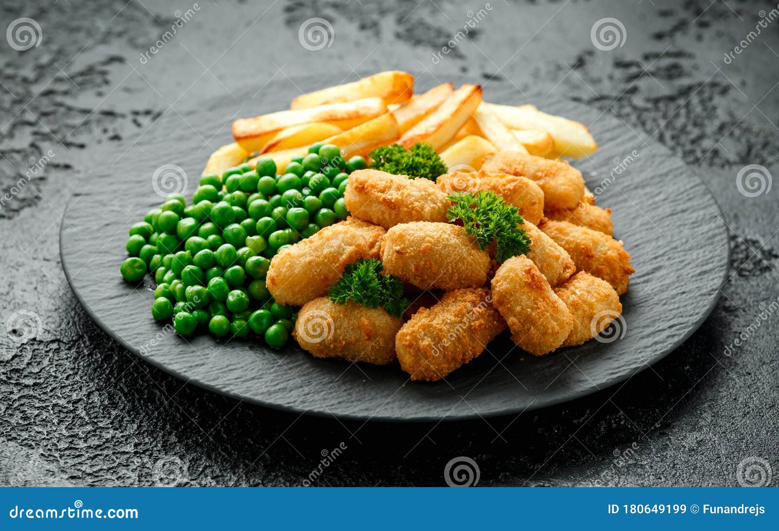 crispy battered scampi nuggets served on slate plate with potato chips and green peas
