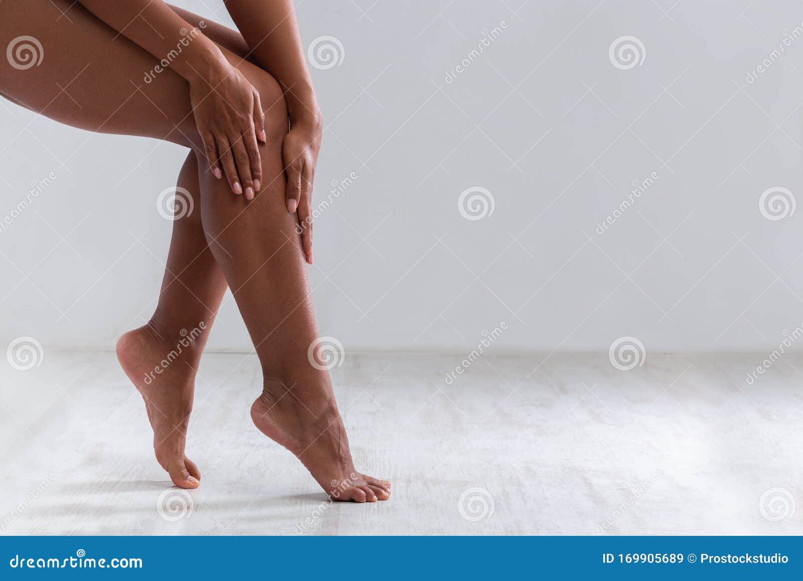 cropped of female legs, woman touching her skin after waxing
