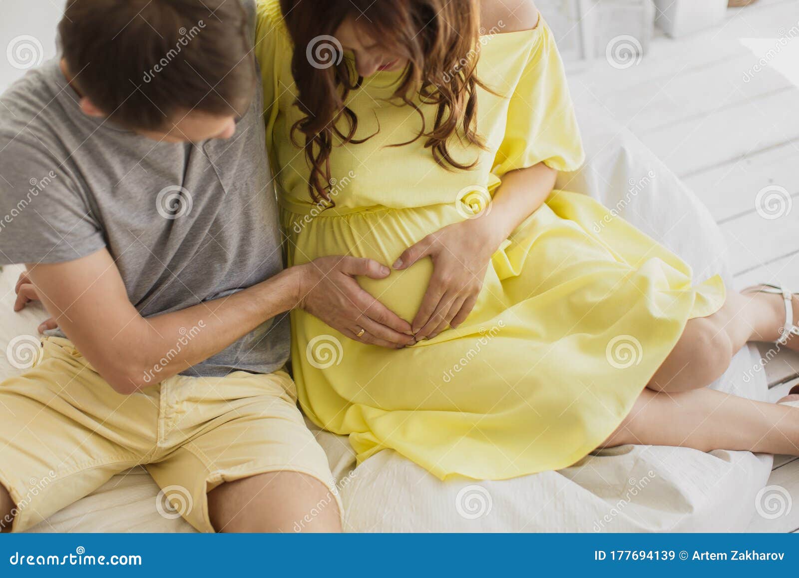 Cropped Image Of Beautiful Pregnant Woman And Her Handsome Husband Hugging The Tummy Stock
