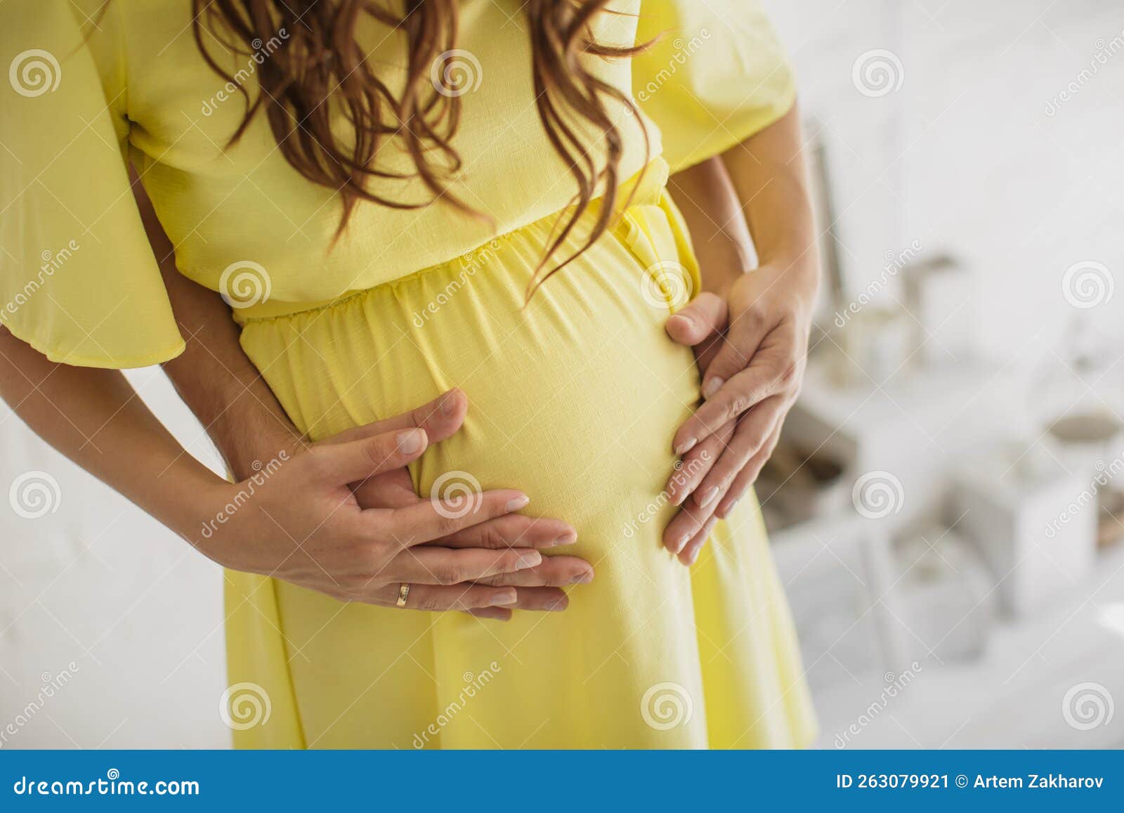 Cropped Image Of Beautiful Pregnant Woman And Her Handsome Husband Hugging The Tummy Stock