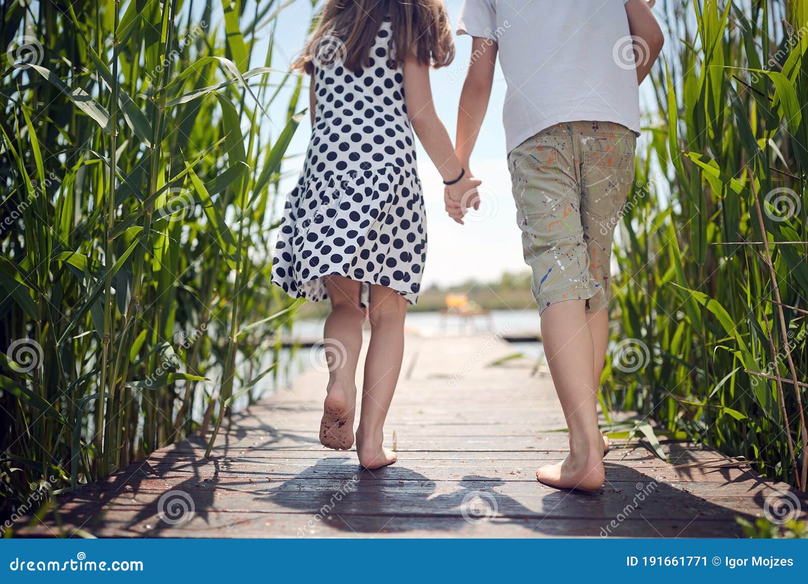 Cropped Image Of Boy And Girl Holding Hands Running Barefoot On Wooden Platform Toward The Water Stock Image Image Of Female Nature