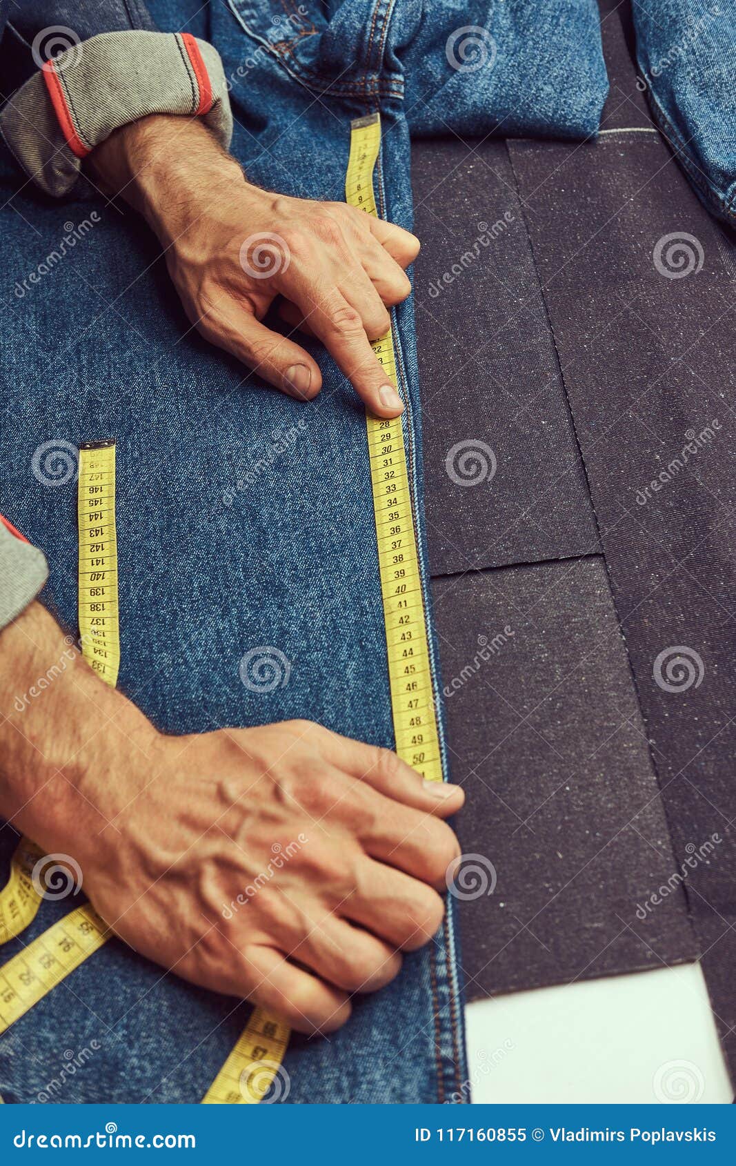 Cropped Image Of A Tailor Makes Measurements Of Jeans Cloth Samples At