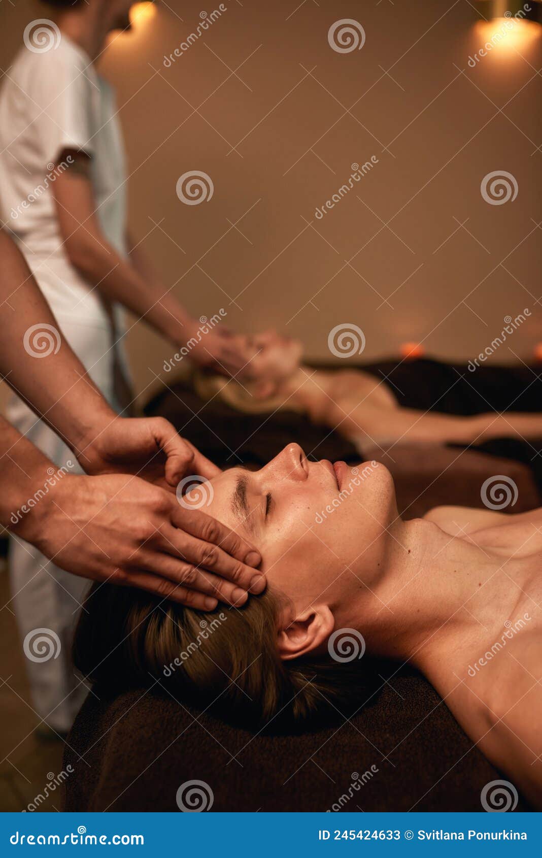 cropped of masseurs doing head massage of couple