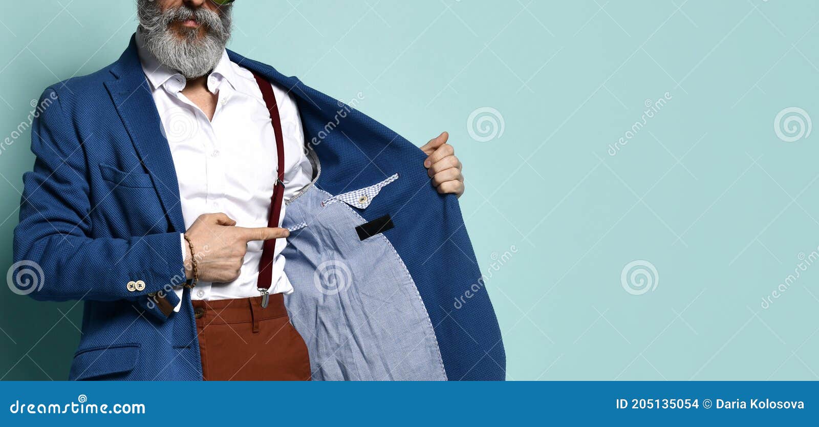 Hopeful casual man looking away with his hand in his pocket while wearing a blue  shirt and brown pants, standing on a coffeeshop background Stock Photo -  Alamy