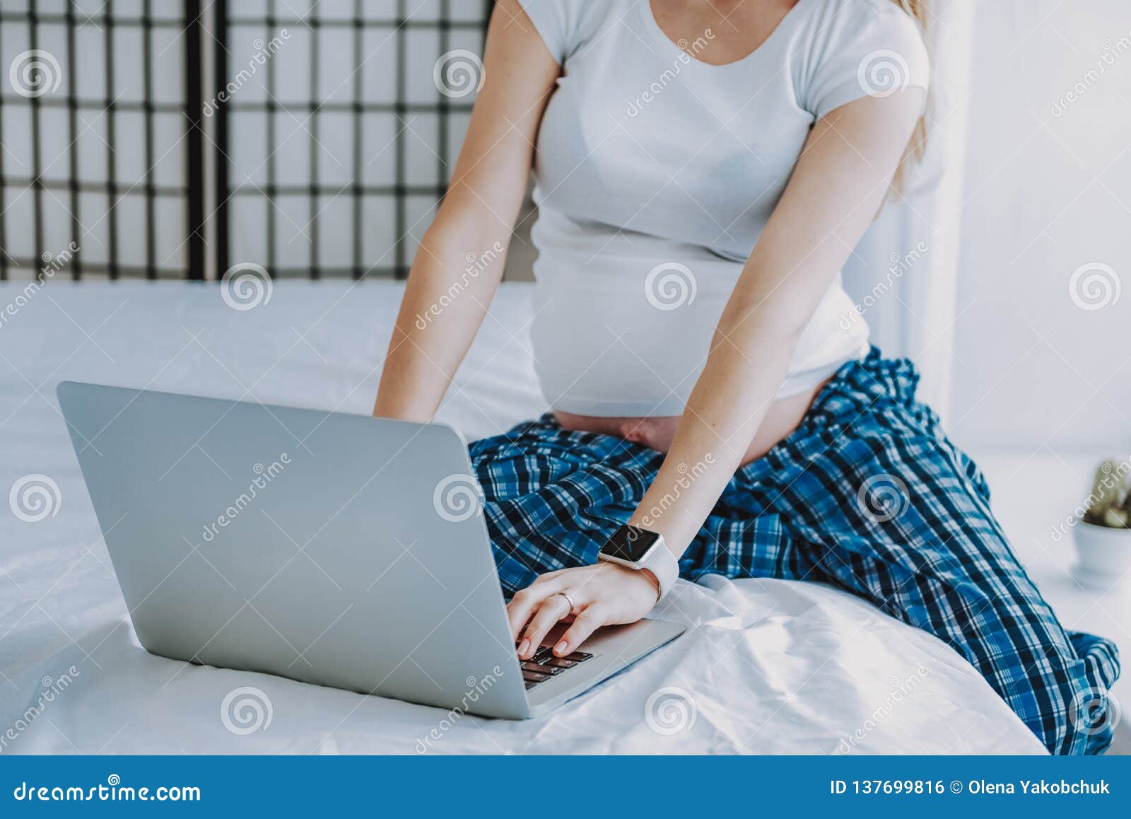 Pregnant Woman Using Laptop On Bed While Resting In Bedroom Stock