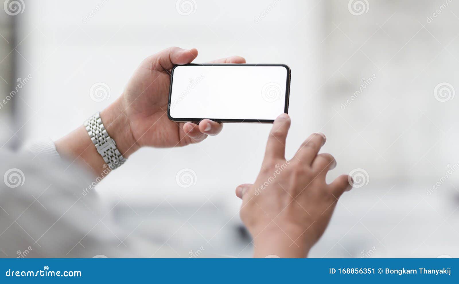 cropped shot of  businessman touching horizontal blank screen smartphone with blurred office room