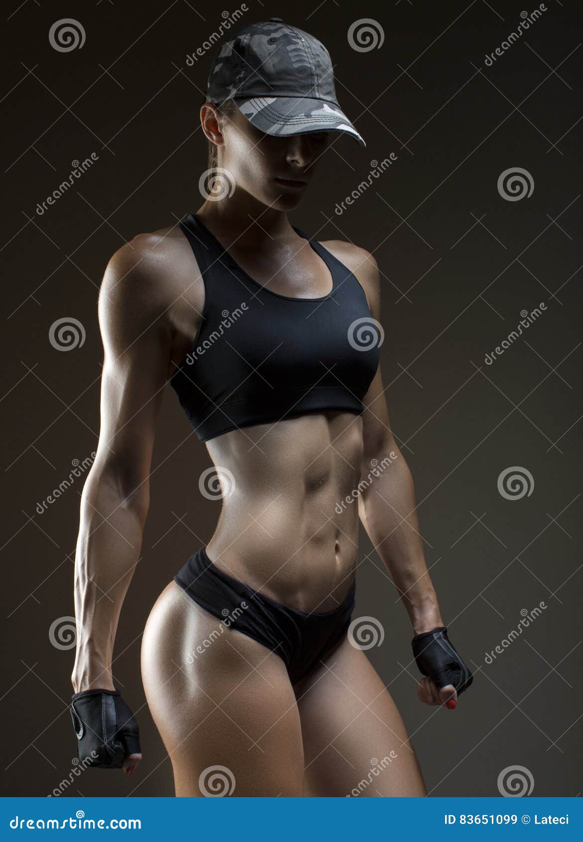 Fotka „Sexy fit woman in a cap posing on red background. Image of fitness  woman in sports clothing. Young female model with muscular body.“ ze služby  Stock