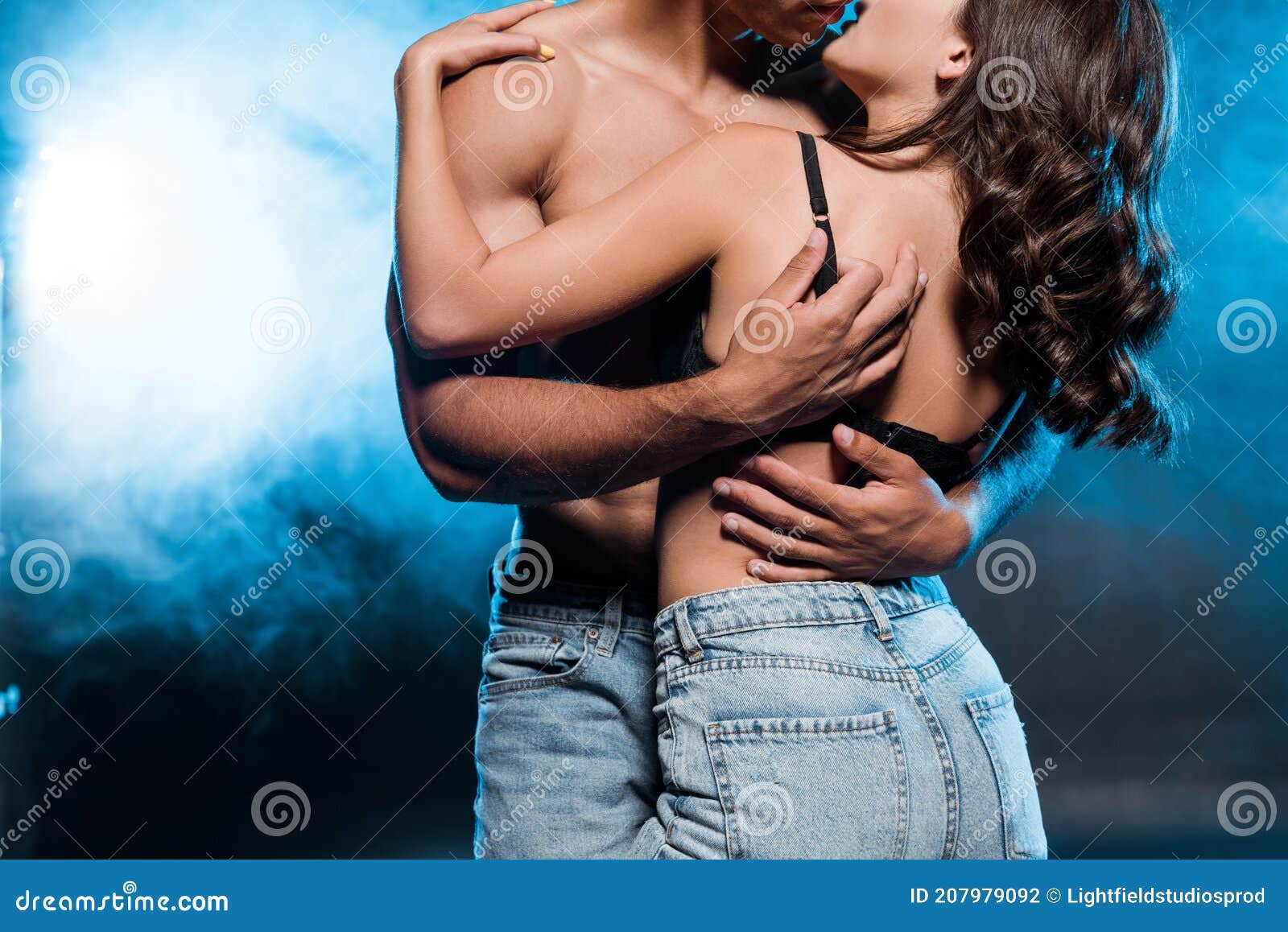 Shirtless Man Hugging Young Woman Standing in Lace Bra on Blue