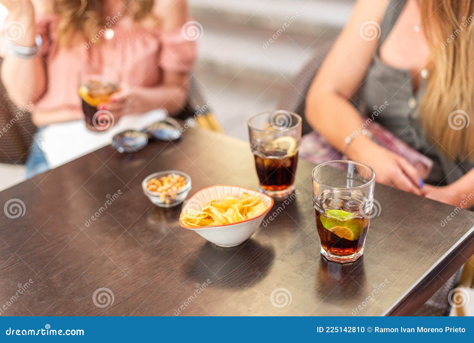 cropped view of some drinks and snacks being consumed by adult friends