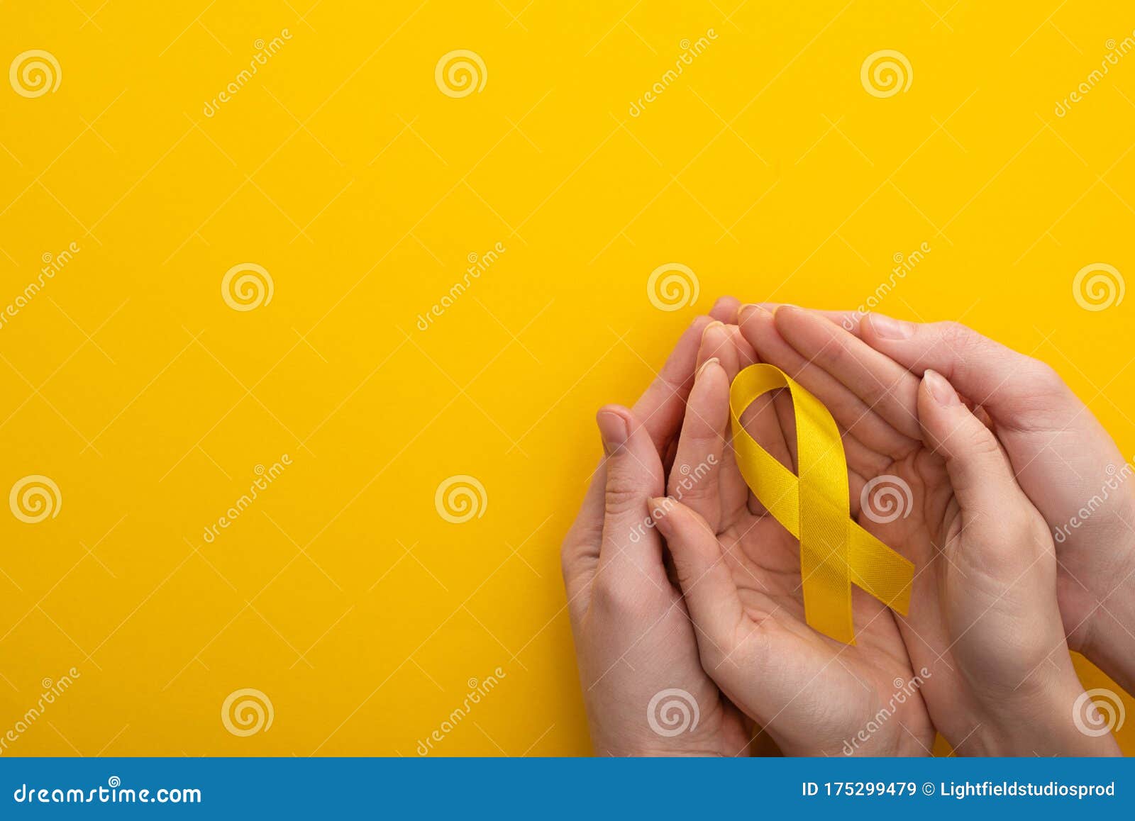 cropped view of woman and man holding yellow ribbon on colorful background, international childhood cancer day concept.