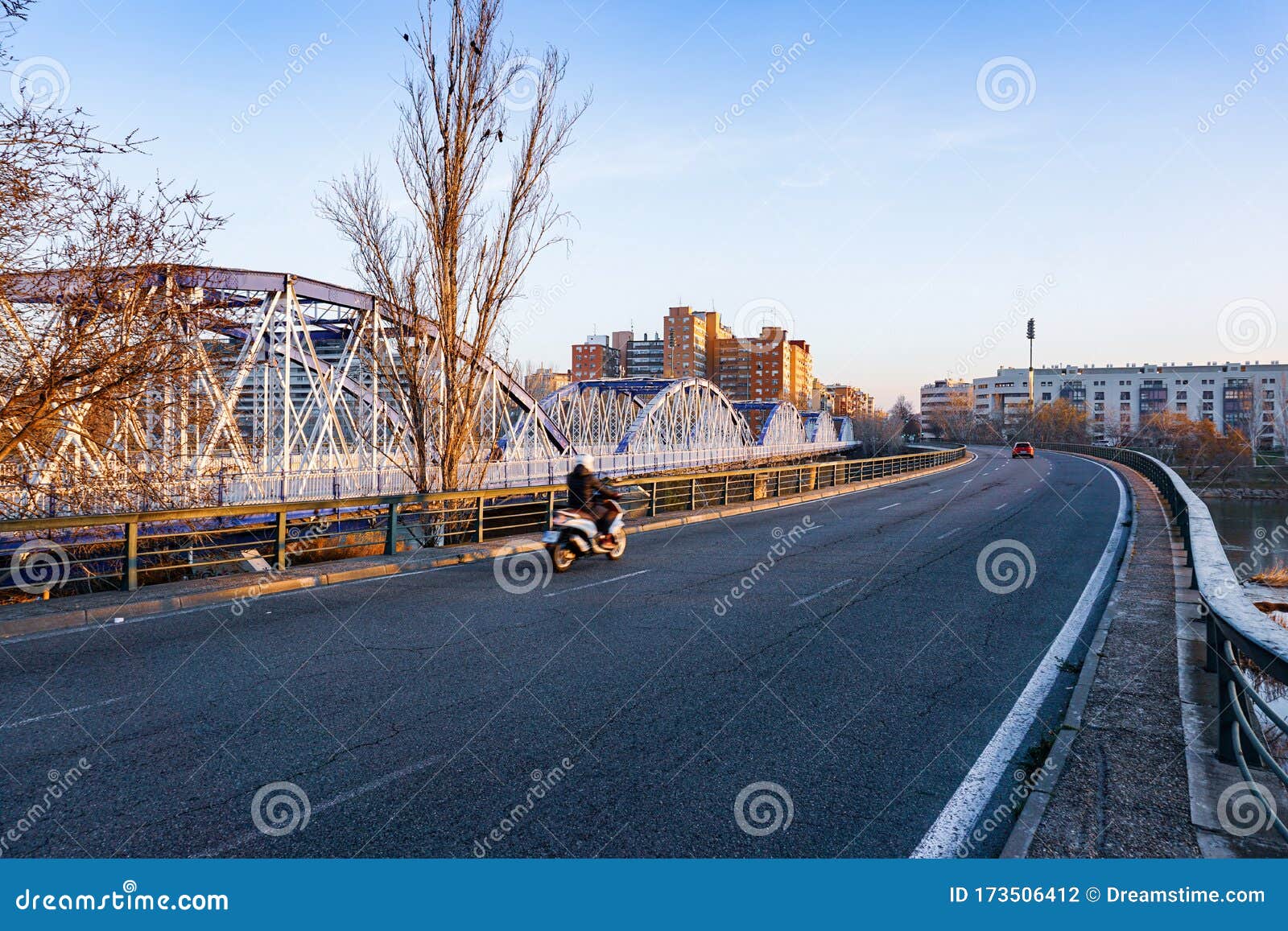 crossing the blue iron bridge in zaragoza by motorcycle at sunrise. .cruzando el puente de hierro azul en zaragoza en moto al
