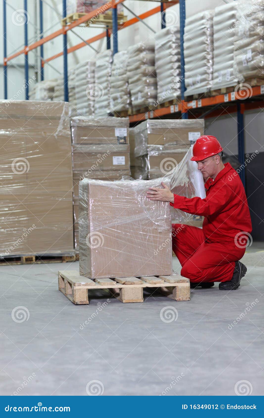 crouching worker wrapping box on pallet