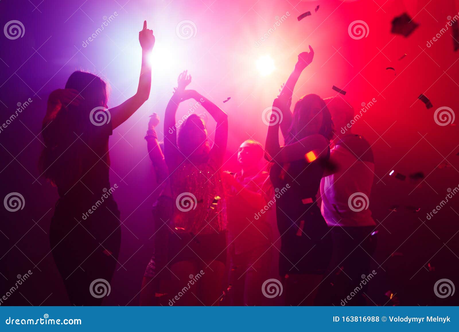 A Crowd of People in Silhouette Raises Their Hands Against Colorful ...