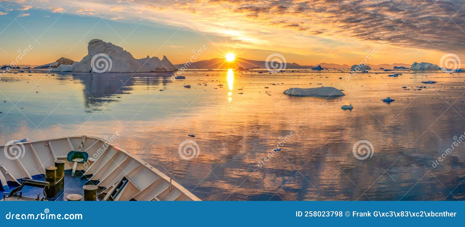 cruise ship sails through wintry cierva cove - antarctica, during a dramatic sunset evening sunset.