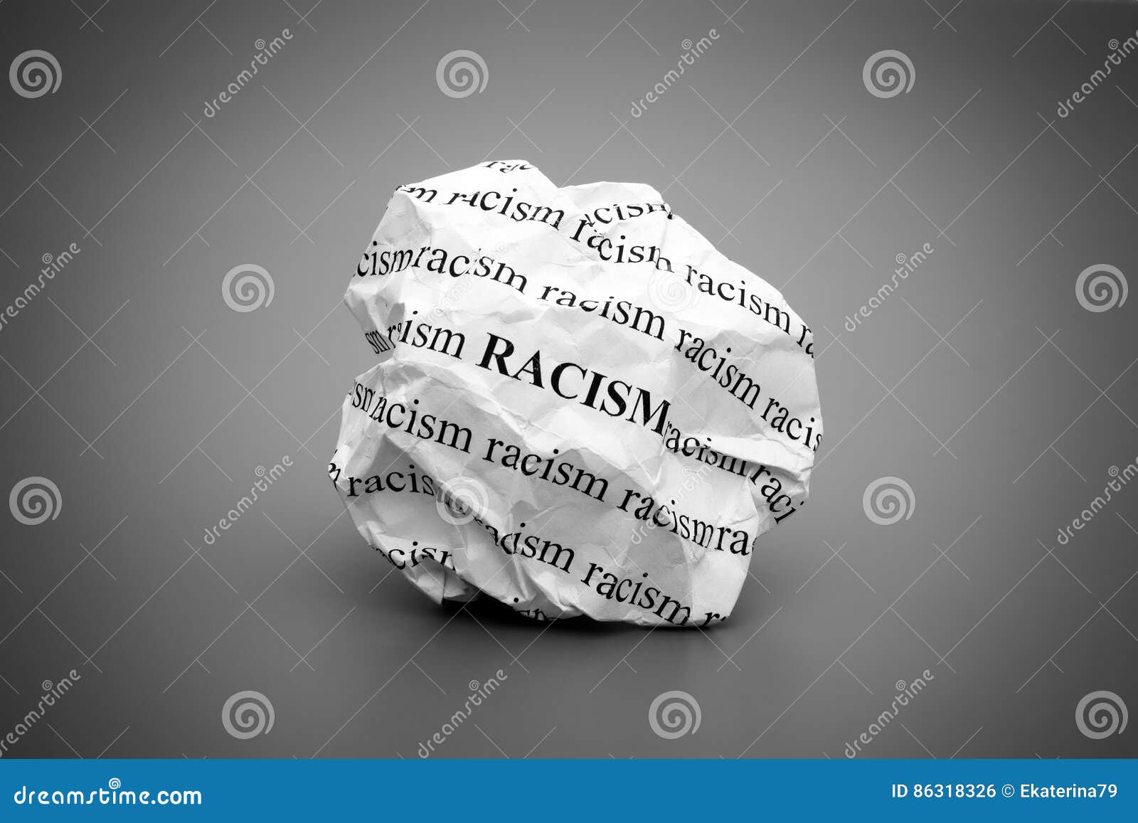 crumpled paper ball with words racism on gray background