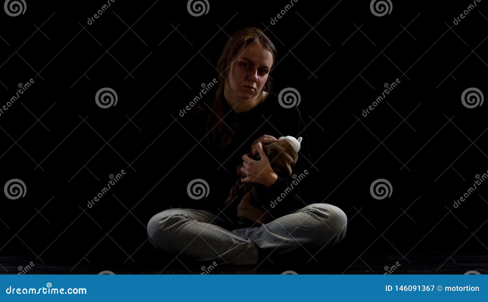 crying depressed lady hugging teddy bear in darkness, obstetric violence victim