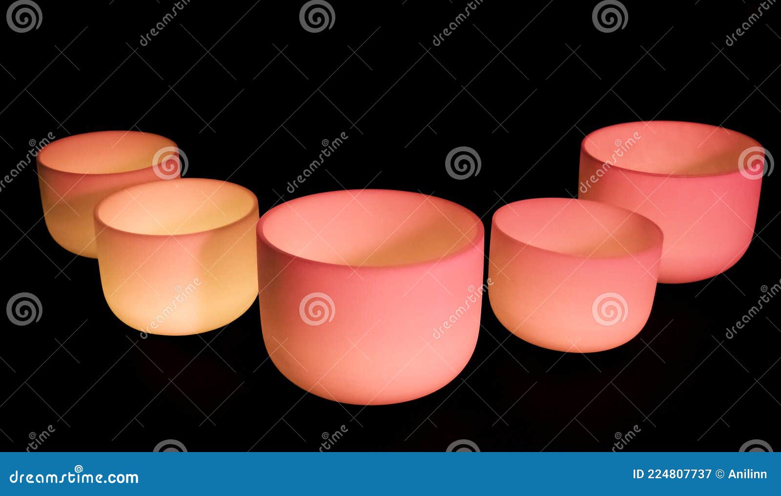 crystal singing bowls with pink light on a dark background